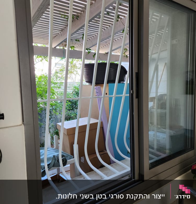 חלון עם סורגי מתכת לבנים ומסגרת אפורה